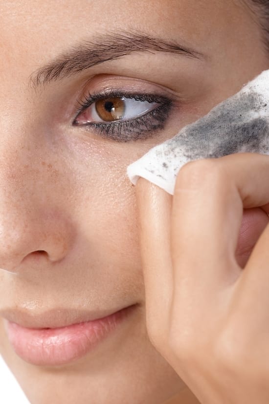 Closeup portrait of young woman removing eye makeup, by cotton pad.