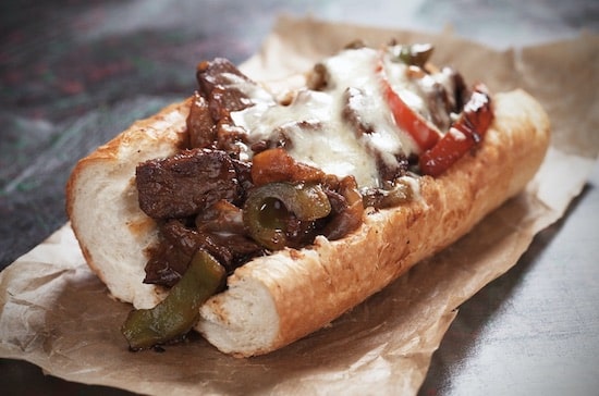 lunch plate with a thick french bread bun with savory french dip crockpot meat peppers, onions and melted cheese 