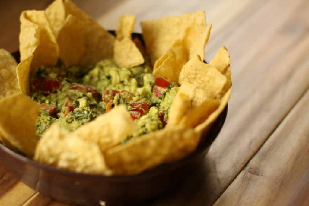 Bowl of avocado dip with chips ready for a party appetizer table