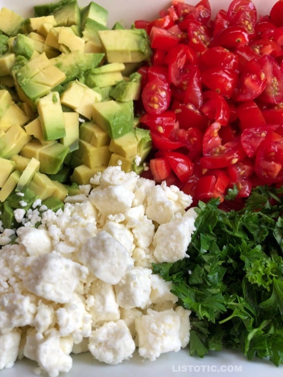 Avocado dip recipe with chopped avocado, diced cherry tomatoes, crumbled feta cheese, minced parsley