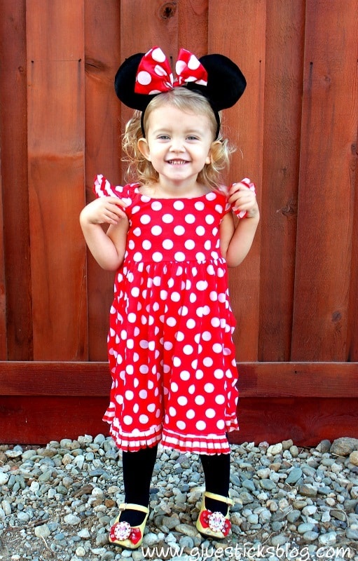 Toddler in Minnie Mouse costume with red polka dot dress and black mouse ears and bow.