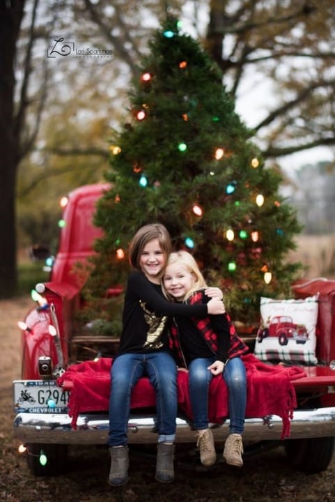 Adorable girls in front of Christmas tree for a greeting card.