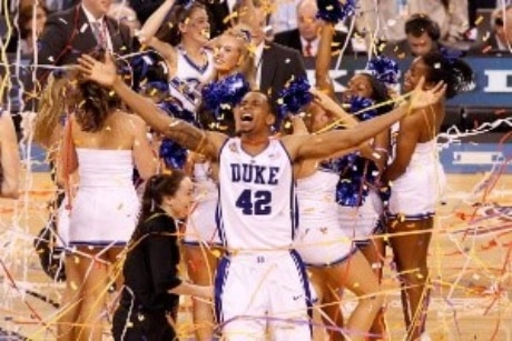 Duke basketball player with arms out and confetti falling as champions of historical March Madness Tournament final four Championship winner.