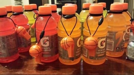 Table full of orange and red Gatorade bottles with basketball whistle for a March Madness Party favor.
