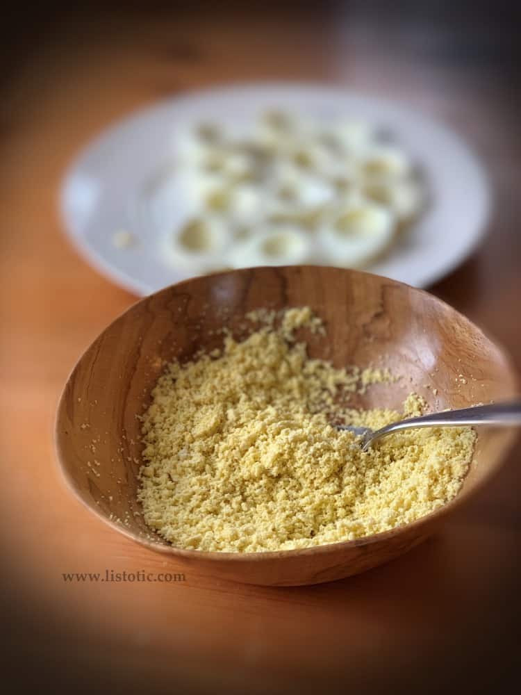 bowl and fork used to crumble the yellow egg yolk of hardboiled eggs prior to adding the ingredients for deviled eggs 