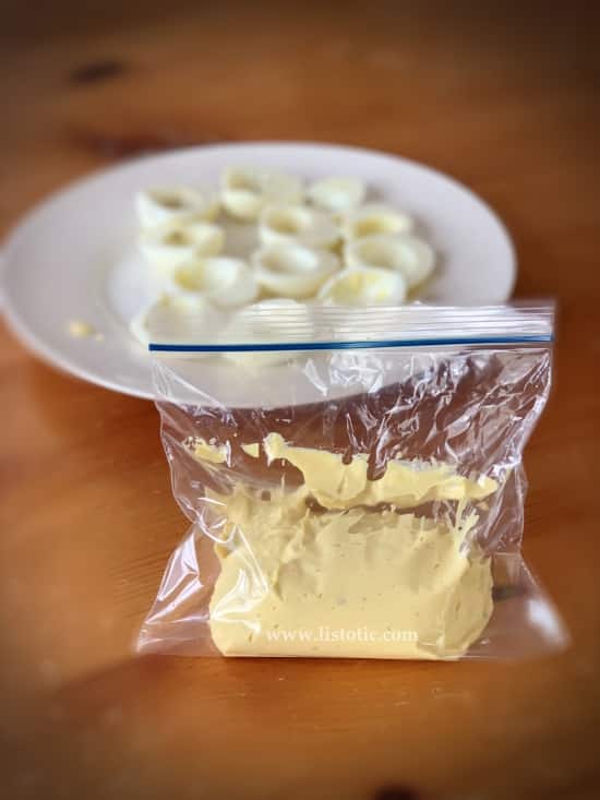 Filling for classic deviled eggs inside a baggie ready to squeeze into the hardboiled white egg yolks