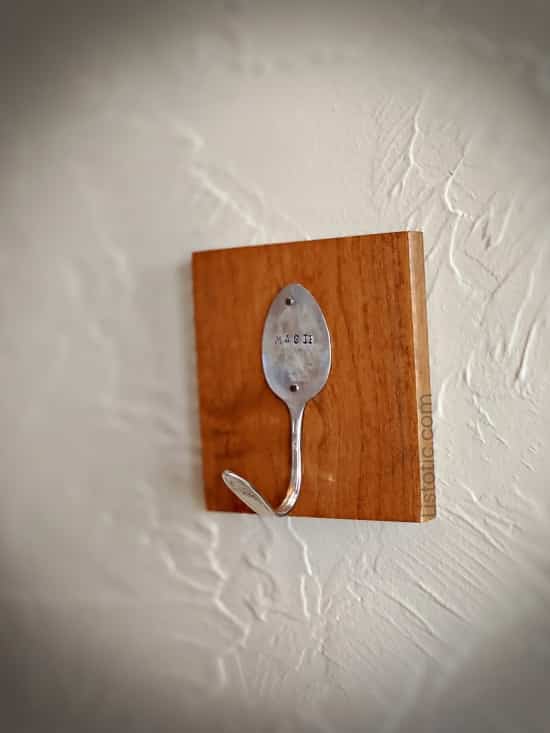 Silver spoon hook craft hanging on a wall.