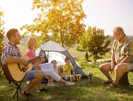 Family enjoying music and nature with their backyard camping adventure. 