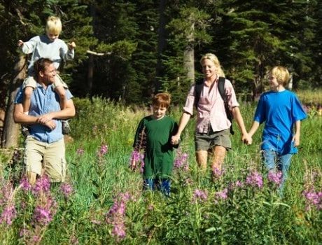 Family of five out hiking in tall grass and trees. Enjoying the outdoors.