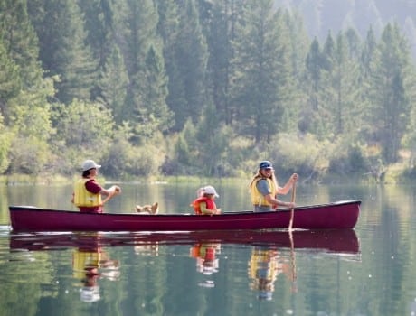 Family plus dog in canoe on a river enjoying the outdoors as a family.