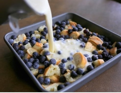 Blueberry breakfast dish being made featuring blueberries, bread crumbs and milk - ready to go in the oven.