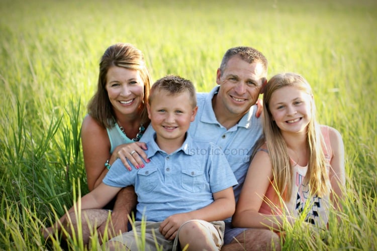family of four posing in grass for a summer family portrait 