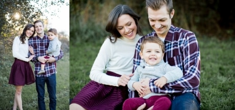 Happy family of three in fall colors at sunset on a autumn night. Dad holding baby sitting on grass and smiling with mom looking on and hugging dad and baby.