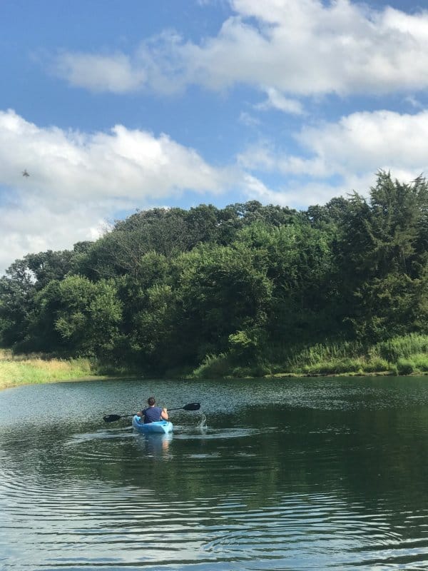 Woman kayaking, enjoying the quiet of a pond and living a happy healthy life.