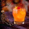 Orange cocktail with skeleton decorations for Halloween.