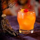 Orange cocktail with skeleton decorations for Halloween.