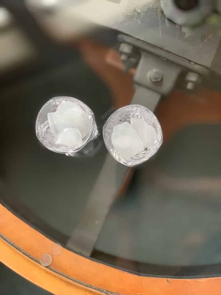 Two glasses filled with ice on a table top.