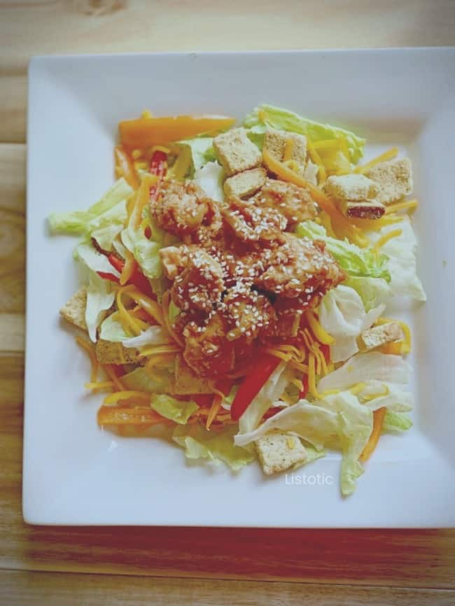 Orange chicken served on lettuce salad.