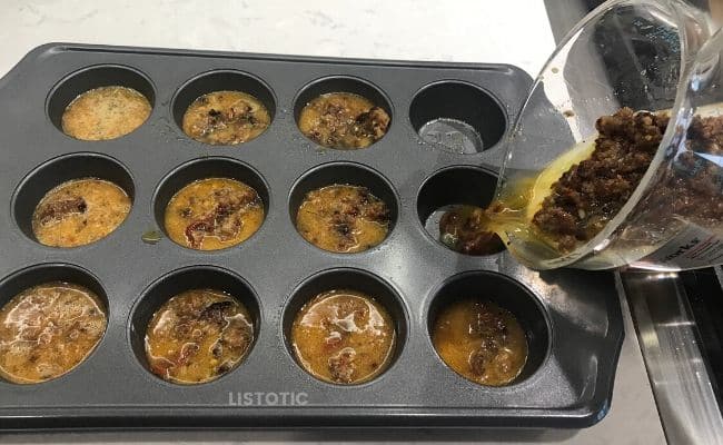 Adding sausage egg mix to muffin pans.