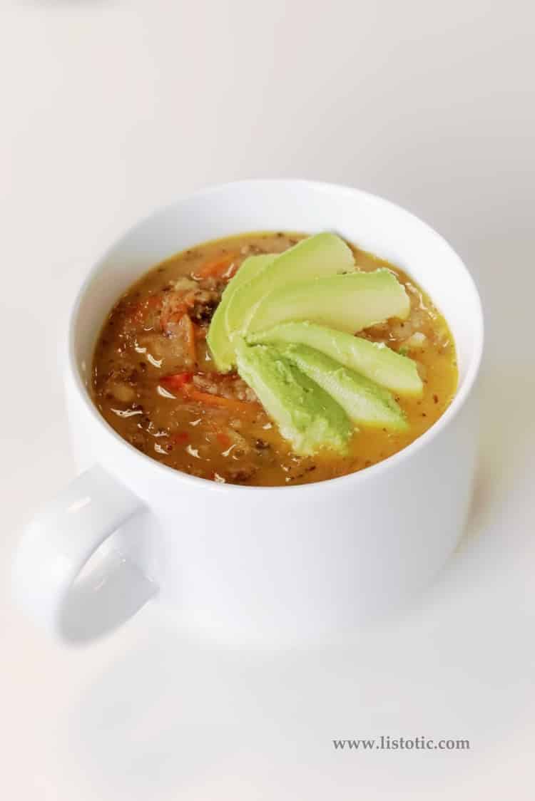 Cup of Cheeseburger soup with avocado on top.