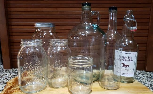 Mason jars, wine bottles and quart bottles for bottling apple pie moonshine.