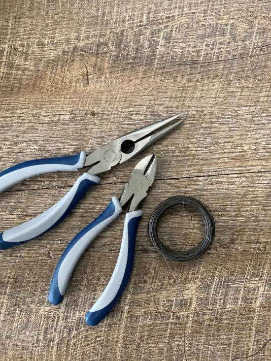 needle nose pliers, wire cutters and 24 gage coiled wire on a table ready for crafting