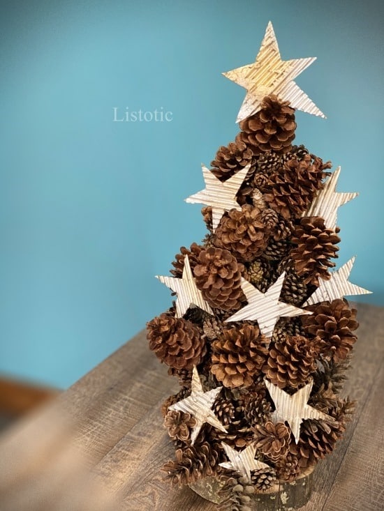 Rustic DIY pinecone Christmas tree with cardboard stars ornaments sitting on a table top