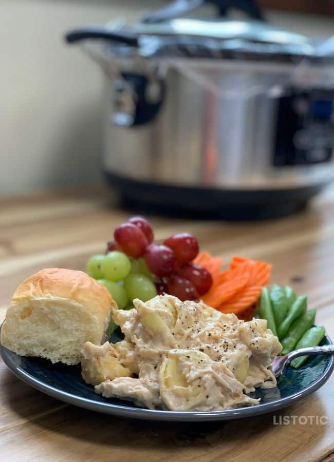 plate of chicken Alfredo with healthy fruits and veggies on a table in front of a slow cooker