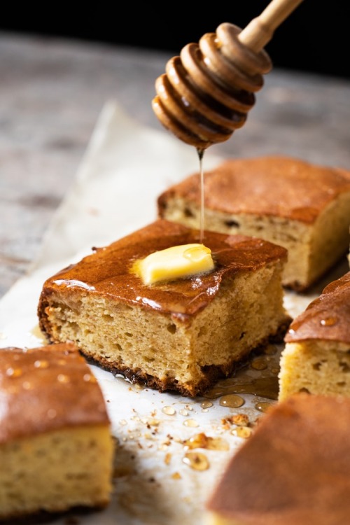 Individual browned grain free cornbread squares on parchment paper drizzled with honey and melted butter for gluten free and keto diets.