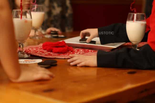 child reaching for an Oreo cookie on a table set for with valentine’s day decorations