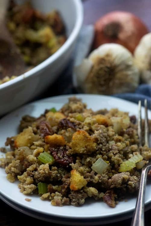 A plate with low carb cornbread, sage sausage, diced onion, diced celery and pecans.