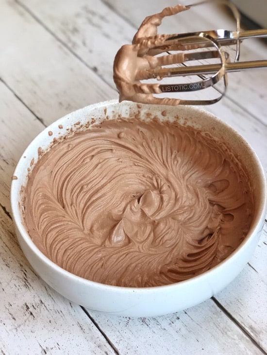 A white bowl containing whipped chocolate frosty ice cream for a keto diet with chocolate frosty on the beaters.