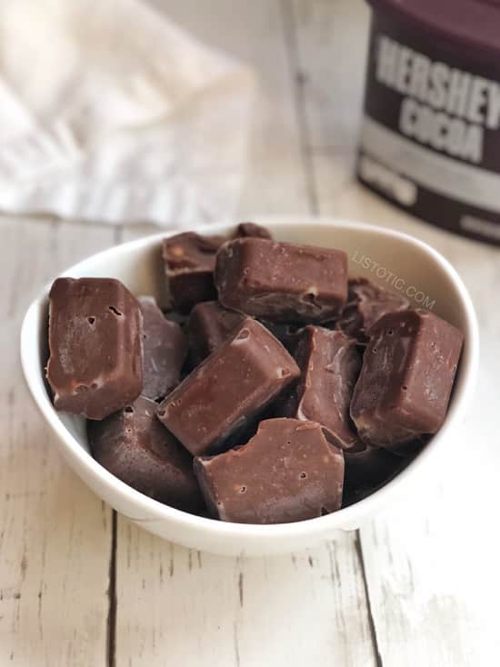 A white bowl containing a dozen small chocolate covered peanut butter squares for a keto diet.