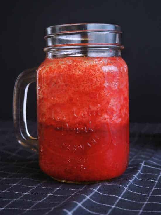 A mason jar containing a strawberry protein smoothie.