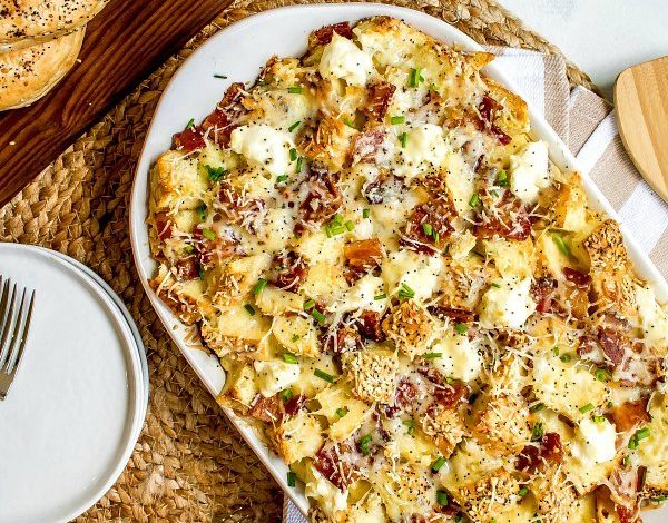 A white serving platter topped with cubed everything bagels topped with cheese and fillings.