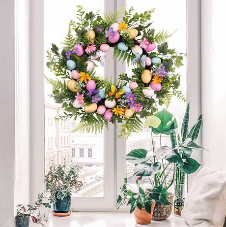 A colorful egg wreath hanging on a window.