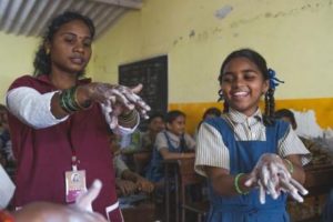 Two school children washing their hands with Soapbox soap. 