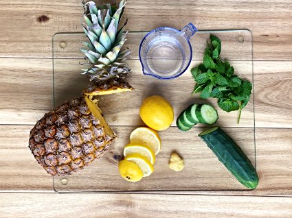 Fat burning drink ingredients of pineapple lemon, mint and cucumber on a cutting board