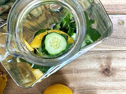 looking down into a glass pitcher with chuncks of pineapple and cucumber 