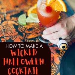 Glass of Bacardi Zombie Drink at a Halloween Celebration Table with hand adding Lime wedge