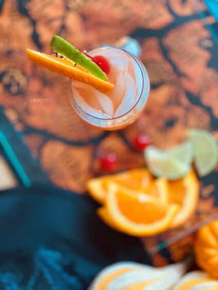 Glass of Zombie Bacardi Drink on a Halloween table garnished with lime, orange and cherry