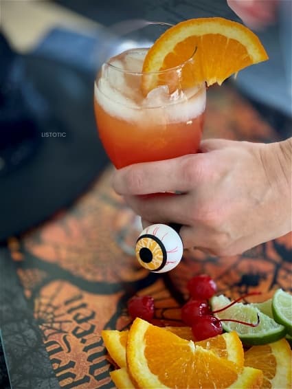 hand holding zombie cocktail drink in a glass with ice