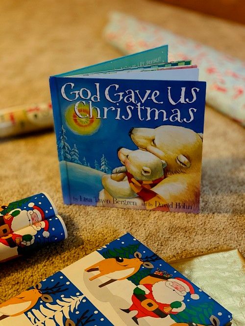 holiday wrapping paper and a children's story book propped up on the ground a Christmas bedtime stories book