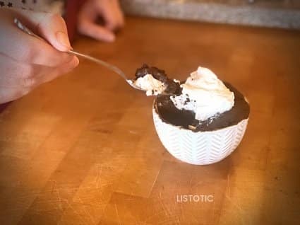 person with spoon taking a bite of chocolate mug cake