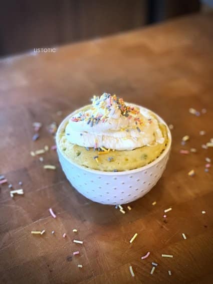Keto funfetti mug cake sitting on a kitchen counter with lots of sprinkles