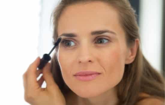 woman looking in mirror with wand near eye