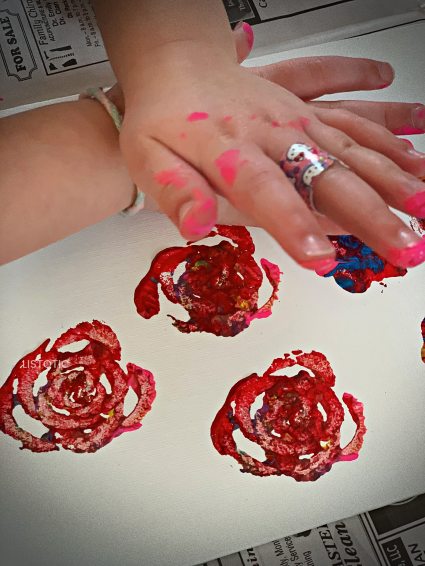 children's hands making a celery rose print with celery stamps