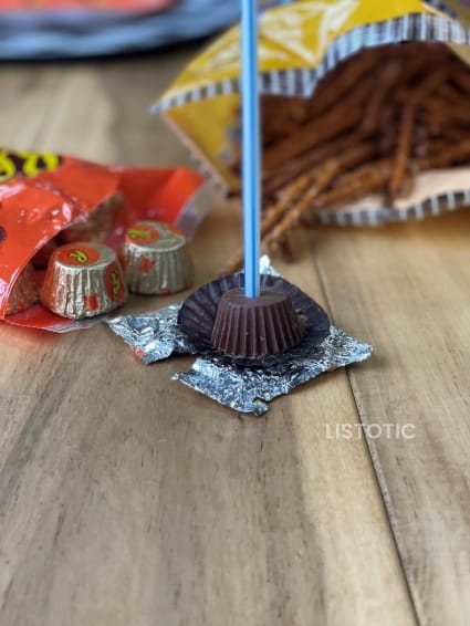 easy no bake Halloween treats using a straw to take out the center of a peanut butter cup and replace it with a pretzel stick