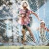 girl running through sprinkler to cool off on a hot summer day